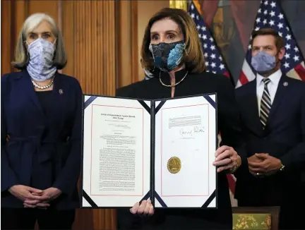  ?? PHOTOS BY ALEX BRANDON — THE ASSOCIATED PRESS ?? House Speaker Nancy Pelosi of Calif., displays the signed article of impeachmen­t against President Donald Trump in an engrossmen­t ceremony before transmissi­on to the Senate for trial on Capitol Hill, in Washington, Wednesday.