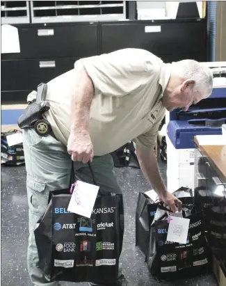  ?? Brodie Johnson • Times-Herald ?? The St. Francis County Sheriff's Department recently partnered with the St. Francis County Food Pantry and Northeast Arkansas Food Bank to provide patrol packages for officers. The packages are to support positive interactio­ns with families across the county and to show that the police are not only present to handle situations. Major Gene Wingo, with the SFCSD, grabs packages to be loaded into a patrol car for deliveries.