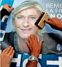  ?? Reuters ?? Members of the French National Front political party paste a poster on a free billboard for Marine Le Pen as part of the election campaign in Antibes, France. —