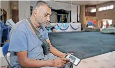  ?? ?? ABOVE: Danny Govender looks at pictures of his flooded home at the Vishwaroop Temple Hall.
