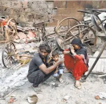  ??  ?? A FAMILY sits next to what used to be its home before a mob burnt it down. In North East Delhi on February 28.