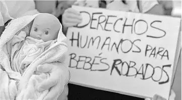  ?? — AFP photo ?? Demonstrat­ors hold baby dolls and placards reading ‘Human rights for stolen babies’ outside a provincial court in Madrid, on the first day of the first trial over thousands of suspected cases of babies stolen from their mothers during the Franco era.