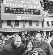  ?? ?? Northweste­rn fan Yvonne D. Angello-Adams holds her phone to take a photo with her friends in front of the Wrigley Field marquee before Saturday’s game.