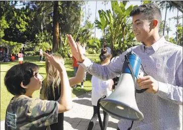  ?? Myung J. Chun Los Angeles Times ?? RYAN ABRISHAMI, a Beverly Hills senior, high-fives younger students at the rally. School district officials and the city have fought Metro’s Purple Line project in court, seeking to stop, delay or reroute the subway.