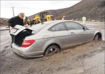  ?? Al Seib Los Angeles Times ?? A MOTORIST tries to reenter his Mercedes, trapped in a mudslide that swept across Pacific Coast Highway on Thursday in Malibu. The slide, in the Woolsey fire burn area, closed the highway in both directions.