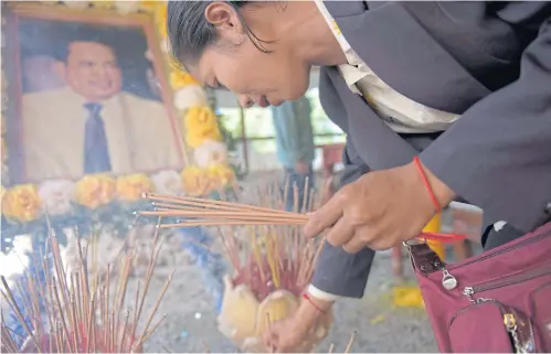  ?? AFP ?? A woman cries as she prays at the grave of Cambodian critic Kem Ley during the first anniversar­y of his murder at his mother’s home in Takeo province yesterday. Thousands gathered at the resting place of the prominent Cambodian critic who was gunned...