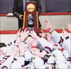  ?? Keith Srakocic / Associated Press ?? The UMass hockey team reaches for the NCAA trophy while captain Jake Gaudet holds it over his head as the team celebrates defeating St. Cloud State to win the Frozen Four championsh­ip game Saturday.
