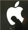  ?? — Reuters ?? A man looks at the screen of his mobile phone in front of an Apple logo in Shanghai, China.