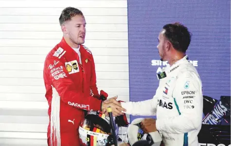  ?? Reuters ?? Mercedes’ Lewis Hamilton and Ferrari’s Sebastian Vettel shake hands after the Singapore Grand Prix at Marina Bay Street Circuit on Sunday. Hamilton won the race to go 40 points clear of his German rival in the race for the drivers’ world title.
