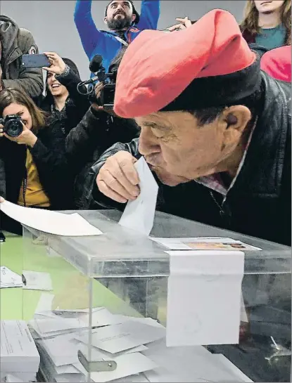  ?? LLUIS GENE / AFP ?? Un elector con barretina besa la papeleta antes de introducir­la en la urna