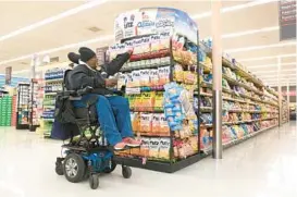 ?? ?? Smith uses the lift feature on his wheelchair to reach higher shelves at the grocery store.