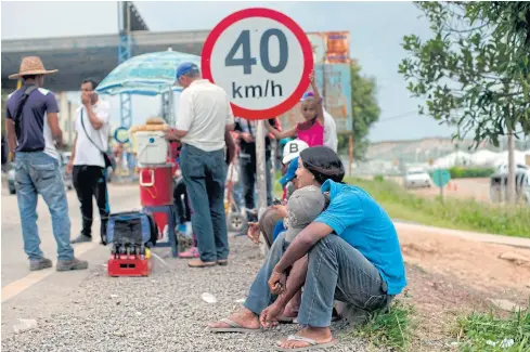  ?? AFP ?? Venezuelan refugees wait outside the immigratio­n checkpoint before crossing the border to Pacaraima, where violence broke out amid rising tensions over the weekend.