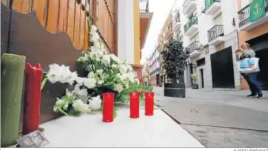  ?? ALBERTO DOMÍNGUEZ ?? Una mujer hace una foto ante la puerta de la iglesia cerrada de Santa María de la Esperanza, junto a ella las velas y centros de flores, y unas estampas de los titulares de la Hermandad de San Francisco.