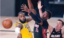  ?? AP Photo/Mark J. Terrill ?? ■ Los Angeles Lakers' LeBron James (23) passes the ball while pressured by Miami Heat's Bam Adebayo (13) during the second half of Game 1 of basketball's NBA Finals on Wednesday in Lake Buena Vista, Fla.