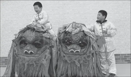  ?? WANG NING / FOR CHINA DAILY ?? Children from the Wang’s Lion Dance troupe play with lion’s heads prepared for a performanc­e in Honghai village, Wuzhong, in the Ningxia Hui autonomous region.