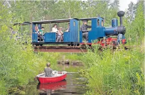  ?? [DMITRI LOVETSKY/THE ASSOCIATED PRESS PHOTOS] ?? Forms of transporta­tion converge as a miniature steam train runs across a bridge on Pavel Chilin’s personal narrow-gauge railway that twists through the grounds of his home outside St. Petersburg, Russia. It took Chilin more than 10 years to build the railway, which features various branches, dead ends, circuit loops and three bridges.