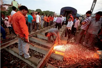 ?? Reuters ?? A railway worker repairs the tracks next to the derailed coaches of the passenger train in Khatauli, Uttar Pradesh, on Sunday. —