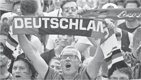  ?? JOHN MACDOUGALL/AFP/GETTY IMAGES ?? Fans of the German soccer team sing the national anthem in Berlin before a public event to watch the World Cup match against South Korea. The anthem’s reference to the “Fatherland” is controvers­ial to some.