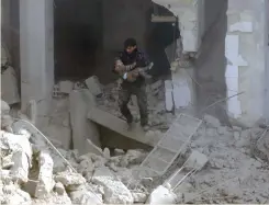  ?? (Bassam Khabieh/Reuters) ?? A MAN CARRIES a wounded child as he walks on debris of damaged buildings, after an airstrike in the eastern Damascus suburb of Ghouta yesterday.