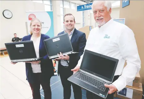  ?? DAN JANISSE ?? The United Way’s Jennifer Soulliere and Liam Giles-hayes and Corporatio­ns for Community Connection­s president Philip Schaus, right, hold laptops at the Via Rail station as part of a program to deliver hundreds of laptops and SMART boards to charities from Windsor to Quebec City.