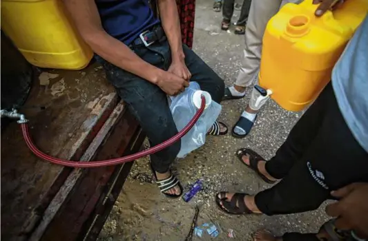  ?? AHMAD SALEM/BLOOMBERG ?? A Palestinia­n boy filled a container with water from a mobile tank in western Khan Younis, Gaza, on Oct. 31.