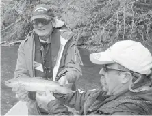  ?? PETER McMULLAN ?? A guide and his guest take time to admire a Cowichan brown trout, a well-establishe­d, non-native species that has thrived since its introducti­on in the early 1930s.