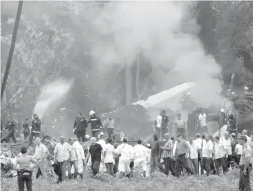  ?? ASSOCIATED PRESS ?? Cuba's President Miguel Diaz-Canel (3rd from left) walks away from the site where a Boeing 737 plummeted into a yuca field with more than 100 passengers on board, just after takeoff from Havana's internatio­nal airport.