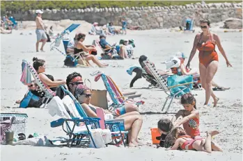  ?? CHARLES KRUPA/AP ?? Beachgoers relax on the shore Friday at Good Harbor Beach in Gloucester, Massachuse­tts.