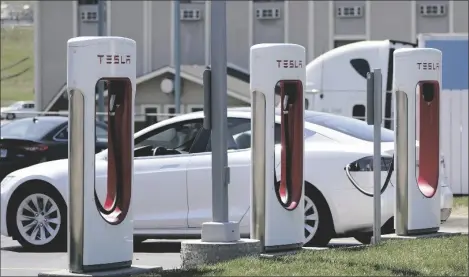  ?? AP PHOTO/ORLIN WAGNER ?? A Tesla charges at a station in Topeka, Kan., in 2021. President Joe Biden and Democrats in Congress are looking to give U.S. automakers with union employees the inside track when it comes to winning the burgeoning electric vehicle market.