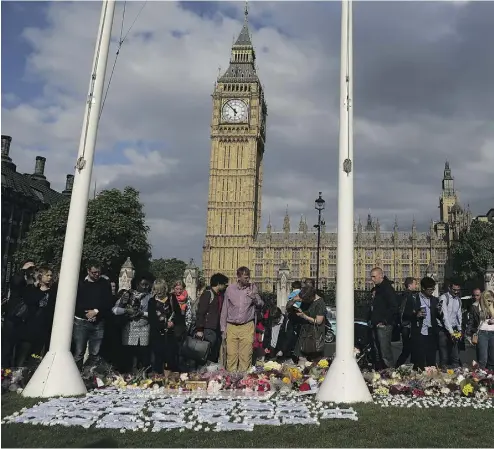  ?? DANIEL LEAL- OLIVAS / AFP / GETTY IMAGES ?? People stop to look at floral tributes and candles laid in remembranc­e of slain Labour MP Jo Cox in Parliament Square in front of the Houses of Parliament in London on Friday.