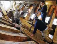  ?? SEAN D. ELLIOT — THE DAY VIA AP ?? In this photo, shipwright­s Trevor Allen, top right, Chris Taylor, bottom right, and Krityavija­y Singh move the stern knee into position to check the fit in the hold of the Mayflower II at Mystic Seaport’s H.B. duPont Preservati­on Shipyard in Mystic,...