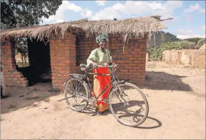  ?? Photos: FAO/ Amos Gumulira ?? Selovana Phiri (above) was able to buy her bicycle thanks to the Social Cash Transfer Programme. Della Demison (left) receiving her cash transfer.