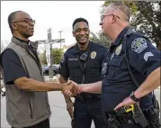  ?? RODOLFO GONZALEZ / FOR AUSTIN AMERICAN-STATESMAN ?? The Very Rev. Matt Iwuji of St. Albert the Great Catholic Church greets Austin police sergeants Lawrence Davis (center) and Chris Hallas before their department’s presentati­on Sunday night on dealing with active shooters.