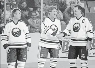  ?? ASSOCIATED PRESS FILE PHOTO ?? Retired Buffalo Sabres linemates, from left, Rene Robert, Richard Martin and Gilbert Perreault, known in the 1970s as the “French Connection,” congratula­te each other as their jerseys are raised in 1995.