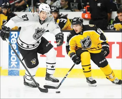  ?? The Associated Press ?? Pittsburgh Penguins forward Sidney Crosby, left, of the Pittsburgh Penguins, moves the puck as Atlantic Division forward Brad Marchand, of the Boston Bruins, reaches in during an NHL All-Star hockey game at Staples Center on Sunday in Los Angeles.