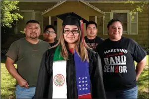  ?? The Associated Press ?? PORT ARTHUR, TEXAS: Maria Mendoza, center, wears her graduation cap and gown as she stands with her family, from left, father Tomas Ahuja, brothers Joel and Emmanuel, and mother Karina, outside their home in Port Arthur, Texas, on May 11. Maria and her family fled Hurricane Harvey in 2017 and ended up helping other families. She says the coronaviru­s pandemic has only strengthen­ed her resolve to become a nurse and made her even more grateful for what she has — especially family. For her, being with them is “everything,” she says.