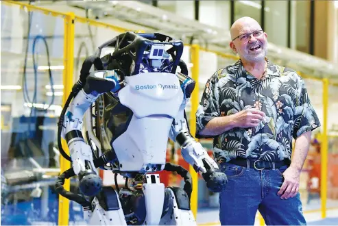  ?? Associated Press ?? Marc Raibert, founder and chair of Boston Dynamics stands beside one of the company’s Atlas robots during an interview and demonstrat­ion Wednesda at their facilities in Waltham, Mass. The company engineered the robot to be able to dance in a fluid manner that is almost human.