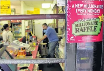  ?? AMY BETH BENNETT/STAFF PHOTOGRAPH­ER ?? Chris Howell atWestern Union News Plus in Tamarac helps a customer. The store sells Florida Lottery’s Millionair­e Raffle tickets, which have been a popular game through the years during the holiday season.