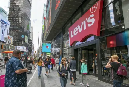  ?? AP PHOTO/RICHARD DREW ?? People pass the Levi’s store in in New York’s Times Square on June 14. Levi Strauss & Co.’s new flagship in Manhattan’s Time Square features larger dressing rooms with call buttons and tailors who can add trims and patches to customers’ jeans.