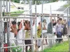  ?? EOIN BLACKWELL /AFP ?? Asylum seekers stand behind a fence in Oscar compound at the Manus Island detention centre in Papua New Guinea, on March 21, 2014.