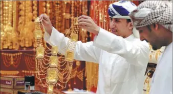  ?? REUTERS ?? A salesman shows a customer gold jewelry in a shop at the Gold Souq in Dubai, United Arab Emirates.