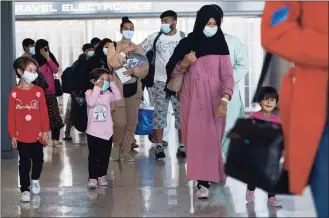  ?? Jose Luis Magana / Associated Press ?? Families evacuated from Kabul, Afghanista­n, walk through the terminal before boarding a bus after they arrived at Washington Dulles Internatio­nal Airport, in Chantilly, Va., on Wednesday.