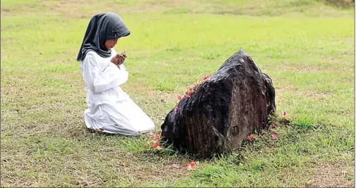  ?? ENO SUNARNO/RAKYAT ACEH/JPG ?? KENANG KELUARGA: Seorang anak berdoa di kuburan masal korban tsunami 2004 kampung Ulee Lheue, Banda Aceh, kemarin.