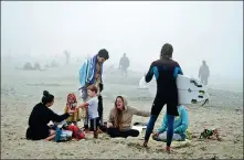  ?? KYLE GRILLOT / REUTERS ?? People sit together at Huntington City Beach in California, the United States, on Saturday, amid the grave situation with the continuing spread of the novel coronaviru­s through the US.