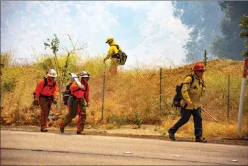  ?? Cory Rubin/The Signal ?? (Above) A camp crew marches in to aid in firefighti­ng efforts to extinguish a fire that broke out near Sierra Highway and Highway 14 on Tuesday. (Below) Los Angeles City Fire 4 drops water on the fire on Tuesday.