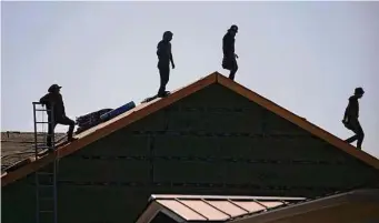  ?? Luke Sharrett/Bloomberg file photo ?? Contractor­s stand on the roof of a house under constructi­on in Louisville, Ky. With fewer buyers competing, the number of active U.S. listings jumped 18.7 percent in June from a year earlier.