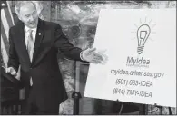  ?? Arkansas Democrat-Gazette/MITCHELL PE MASILUN ?? Gov. Asa Hutchinson shows the new logo and contact informatio­n for the MyIdea project at the state Capitol on Thursday. People, by telephone or website, can make suggestion­s for state government improvemen­ts.