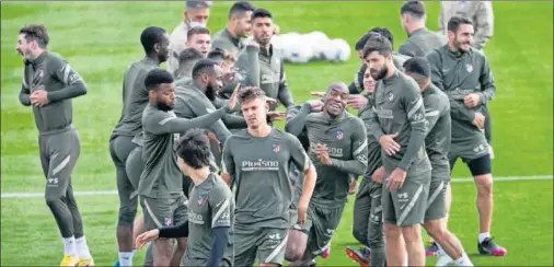  ??  ?? Los jugadores del Atlético bromean durante la sesión de entrenamie­nto de ayer.