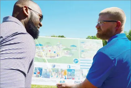  ?? TAMMY KEITH/RIVER VALLEY & OZARK EDITION ?? Leo Cummings III, left, director of member engagement for the Conway Area Chamber of Commerce, and Derek Cox, assistant director of Conway Parks and Recreation, look at the plans for the city’s first splash pad during a groundbrea­king for the project...