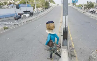  ?? AP PHOTO/ODELYN JOSEPH ?? A street vendor crosses a street Monday in Port-au-Prince, Haiti. The street is empty due to residents staying home amid gang violence.